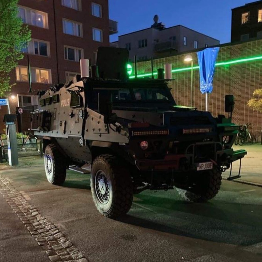 Evening scene featuring a large black armored truck parked in a residential area.