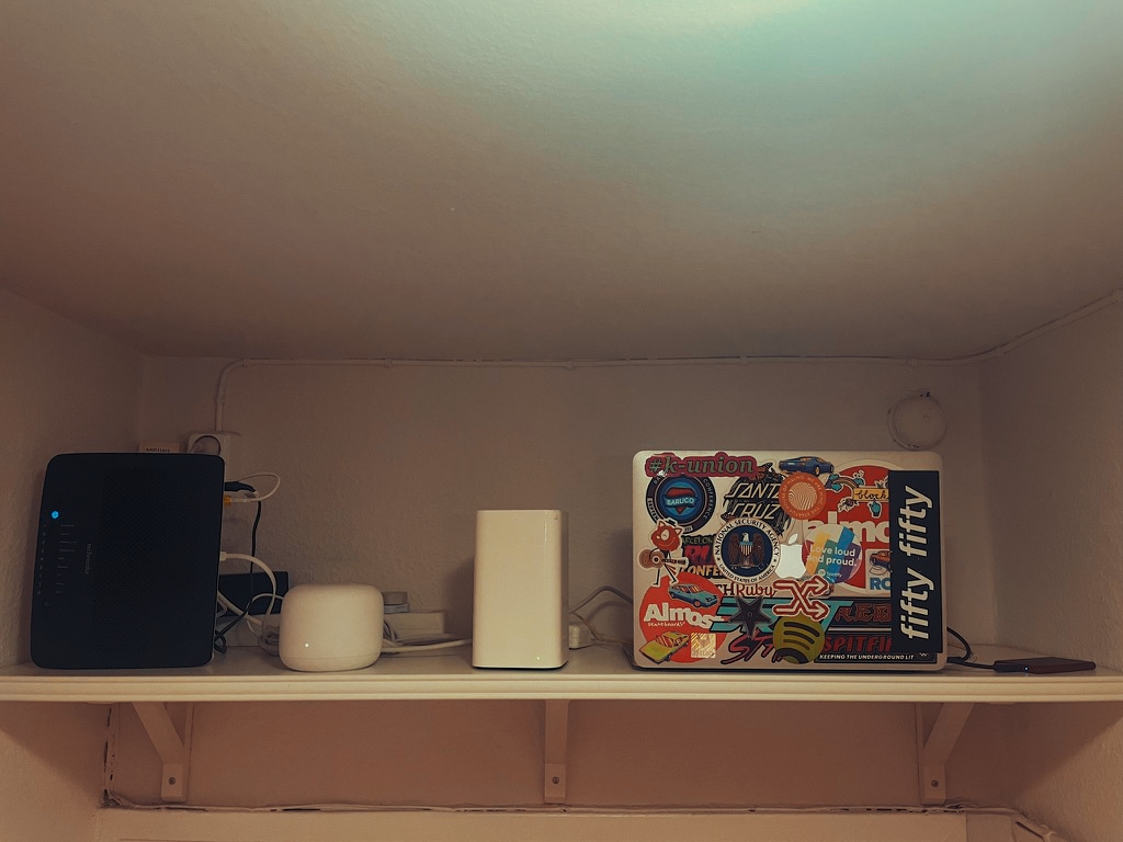 Router, laptop and other computer equipment sitting together on a shelf