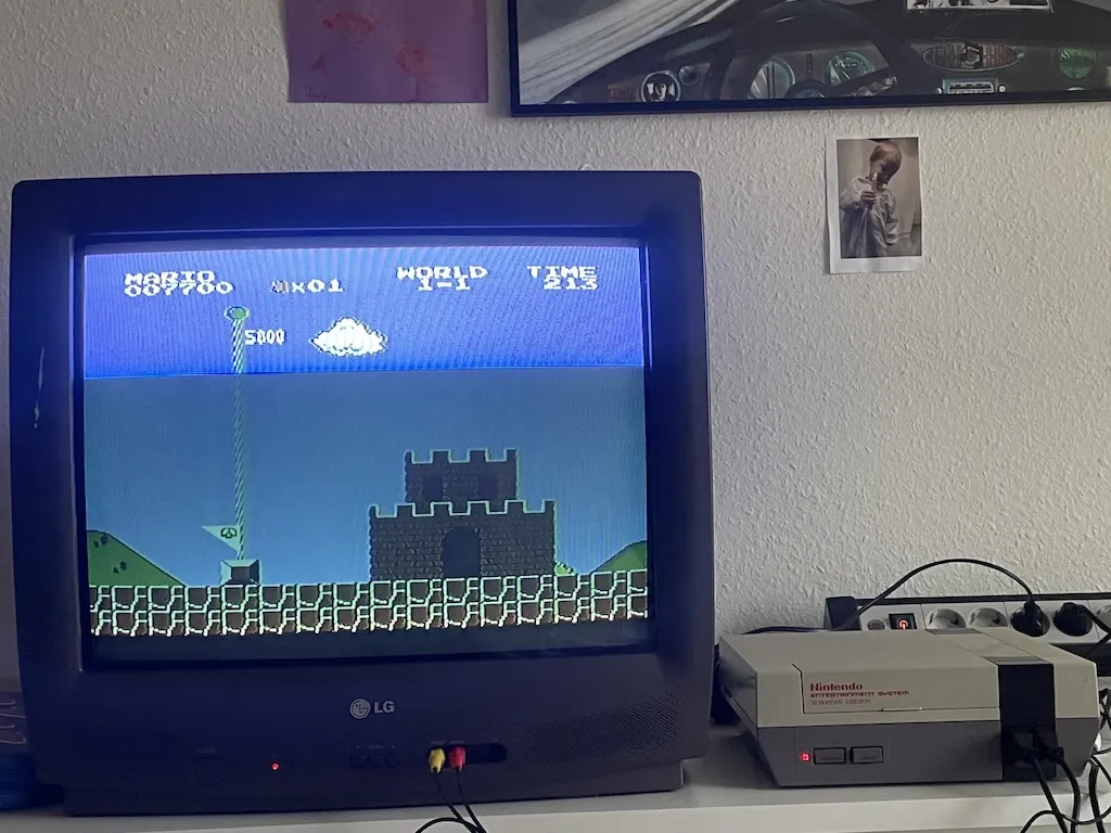 A CRT television next to a powered-on NES. Super Mario Bros is playing on the TV.