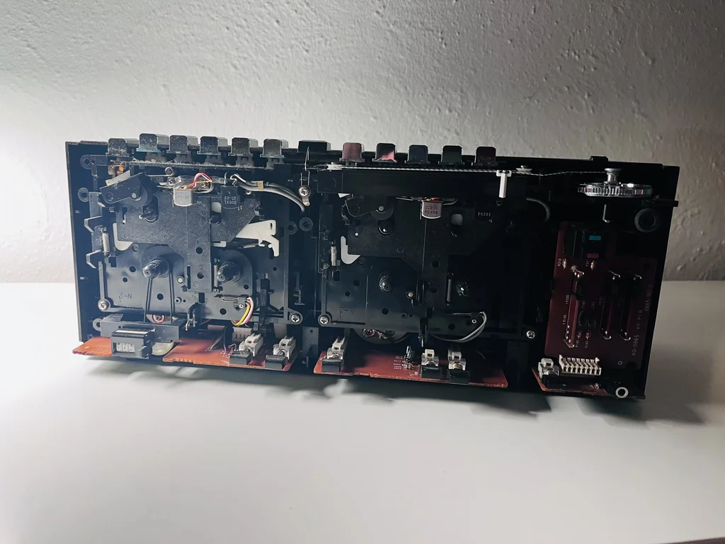 Disassembled boombox with the front removed. Circuit boards and tape decks and other internals are visible.