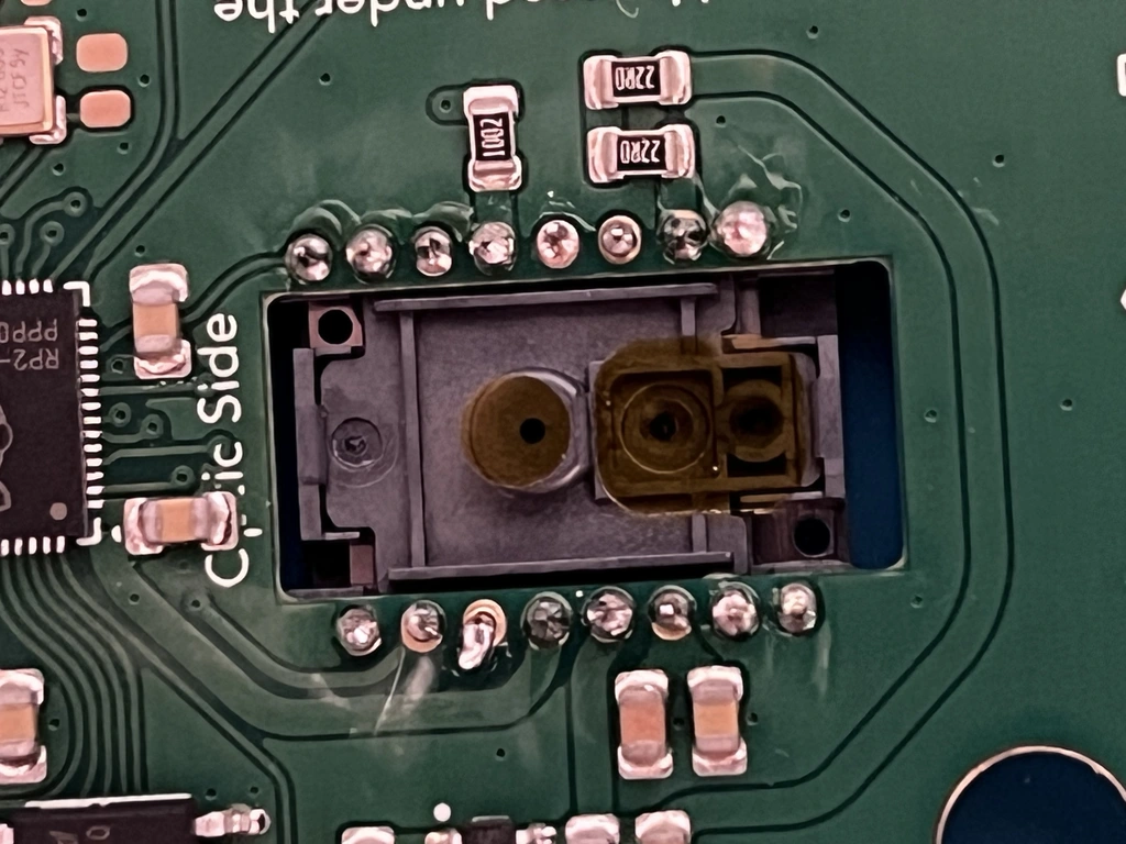 Close-up of some solder joints on a PCB. One or two of the joints are visibly not soldered well, with solder only on the leg of the chip.
