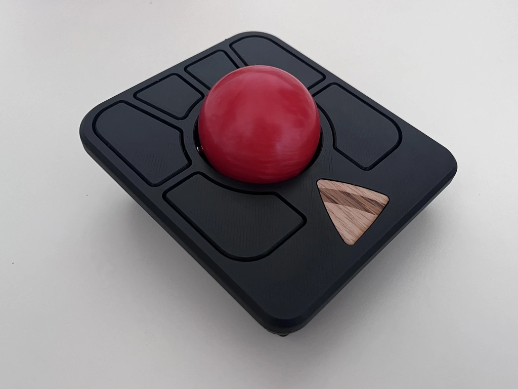 A profile view of a trackball mouse with a black case and a red ball.